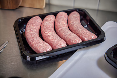 Raw sausages in a black meat tray container