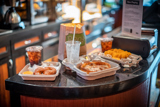 movie theater snacks like popcorn, baked pretzels, personal pizzas, nachos with cheese, and colas in fresh food and beverage packaging	