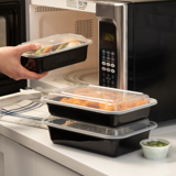 microwavable takeout containers stacked up on top of each other next to a microwave	