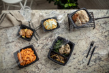 Takeout containers with a variety of foods displayed on a granite countertop