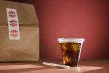 dark cola with ice in a small clear cold beverage cup with a straw