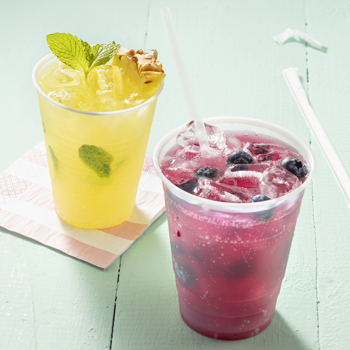 two clear cups with iced beverages inside	