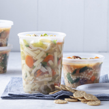 chicken noodle soup in a tall round clear takeout container and minestrone soup in a small round clear takeout container