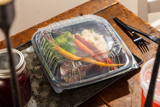 dinner food at a dining table in a two piece takeout container	