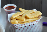 boat shaped container with french fries inside and a side of ketchup	