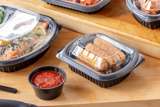 Mozzarella sticks in a small rectangular takeout container good for crispy foods	