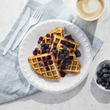 warm latte with sliced blueberry waffles on a white plate