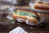 clear hinge lid hot dog container with a chicago style hot dog inside