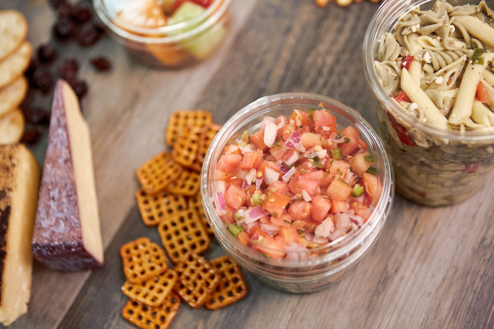 Recycleware round deli lifestyle containers with pico de gallo inside one and pasta salad inside the other