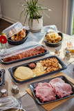 Variety of hot foods in a variety of take out containers displayed on a sunny dining table