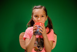 child smiling and holding a beverage in a printed cup with a straw	