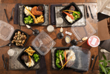 dinner foods on a dining table in hinge lid take out containers