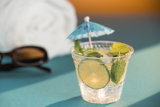 Small clear cup with an iced beverage inside with a tropical decorative umbrella