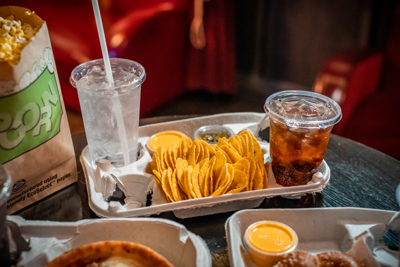 movie theater snacks like popcorn, baked pretzels, personal pizzas, nachos with cheese, and colas in fresh food and beverage packaging	