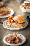 burger sitting on a white divider plate with spots for two sides	