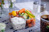 square shaped clear container with fresh veggies and a section with ranch dip