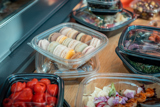 variety of different foods in different take out containers including a clear container with two dozen Macarons