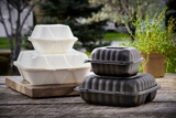 two different size white takeout containers stacked on top of each other and two different size black takeout containers stacked on top of each other