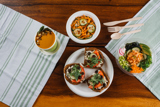 soup, sliced veggies, cucumber and carrot salad, and vegetarian toast on different kinds of compostable plates and bowls	