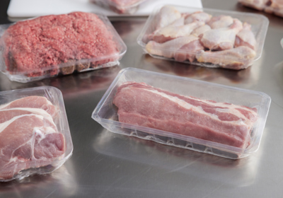 Variety of raw meats in clear meat trays	