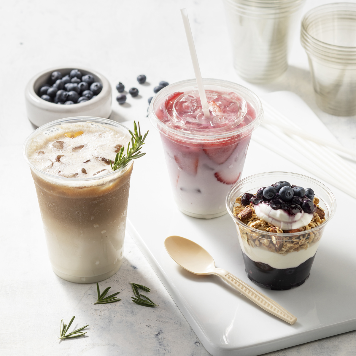 three different kinds of clear cups, one with iced coffee, one with a strawberry beverage, and one with a yogurt parfait