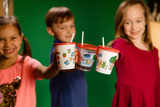 children smiling and holding a beverage in a printed cup with a straw	