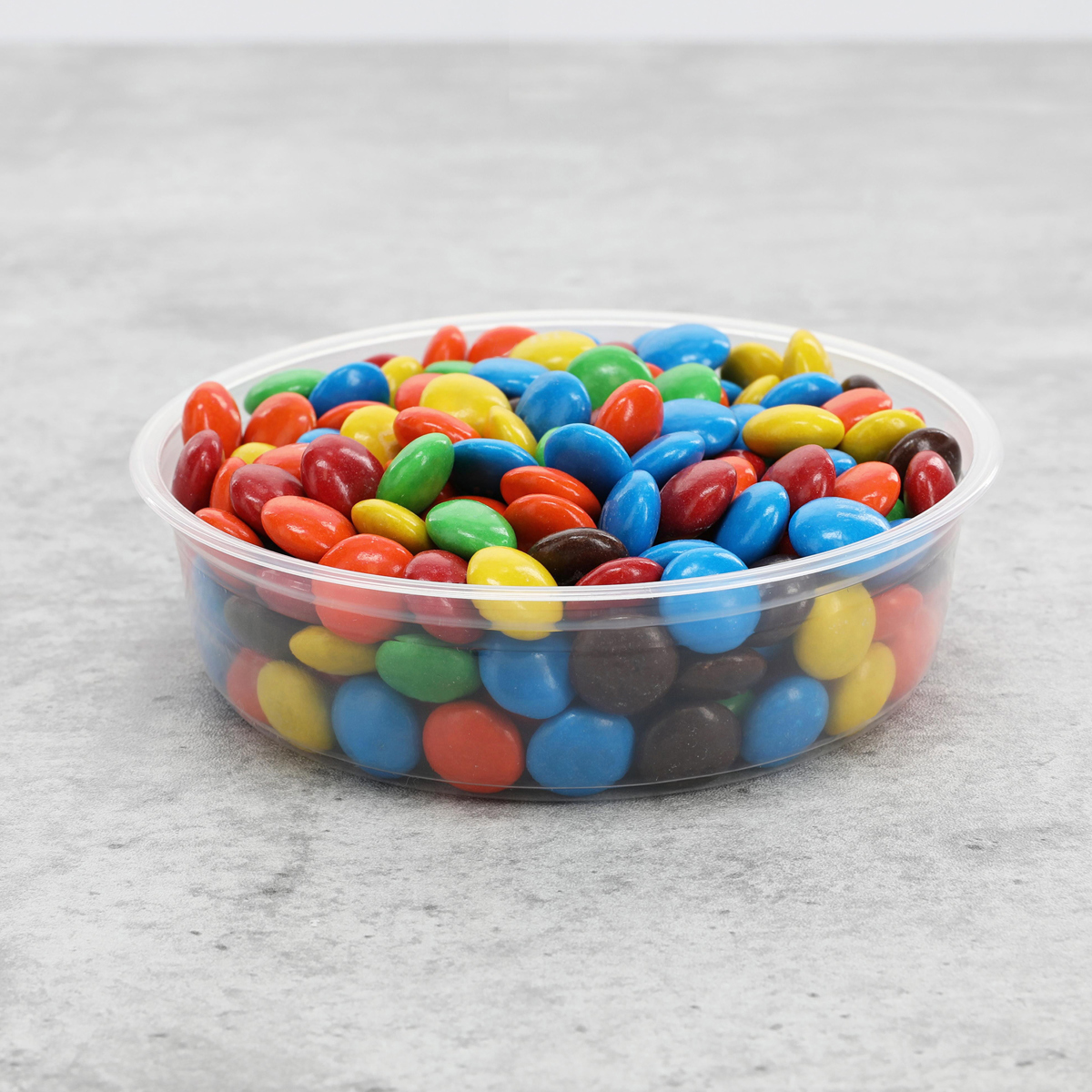 small clear round container with m&ms inside