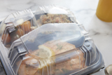 salmon entree in a hinge lid take out container with compartments for the entree and two sides	