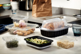 variety of dinner foods in take out containers sitting on a kitchen counter	