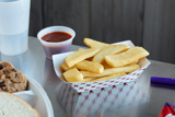 boat shaped container with french fries inside and a side of ketchup	