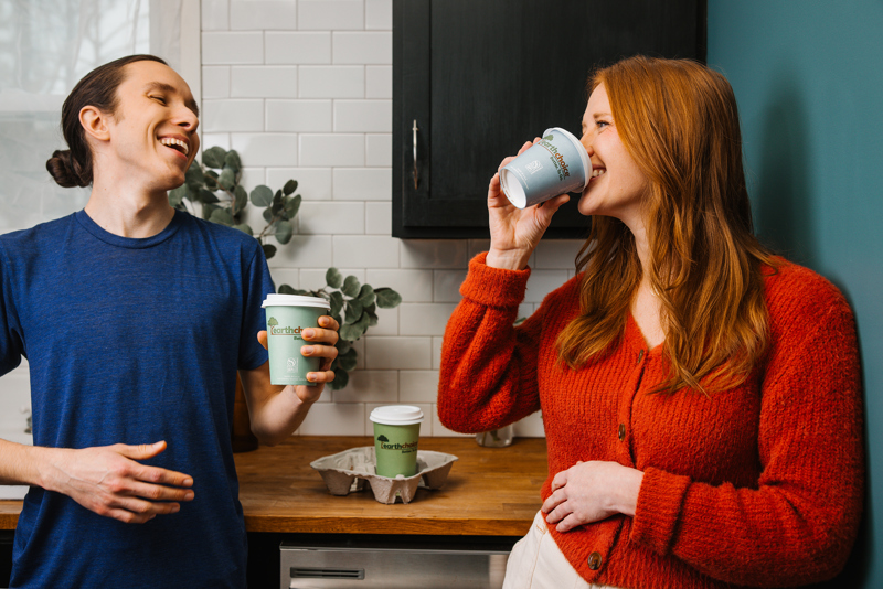 two people in a kitchen smiling and talking with earth choice coffee cups