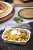 tater tots in a white rectangular takeout container with a clear lid	