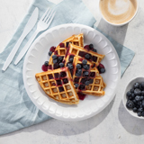 warm latte and sliced blueberry waffles on a white plate	