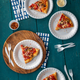 slices of veggie pizza on small white plates sitting on a dining table	