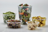 five different size round clear containers with different kinds of deli salads and pasta salads inside