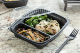 chicken with a side of kale and roasted eggplant in a divider takeout container