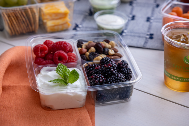 Clear container with 4 square compartments for raspberries, blackberries, nuts, and yogurt