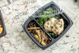 chicken with a side of kale and roasted eggplant in a divider takeout container	