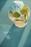 Small clear cup with an iced beverage inside with a tropical decorative umbrella