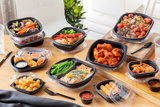 variety of different dinner foods in different types of takeout containers sitting on a kitchen counter top	